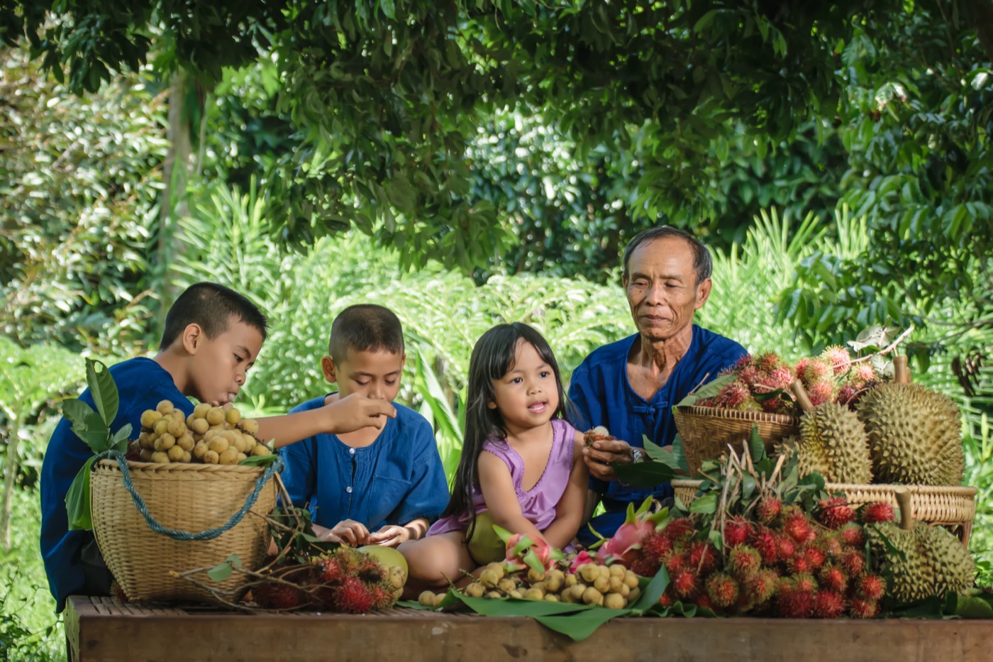 A family around baskets of durian, rambutan and longan