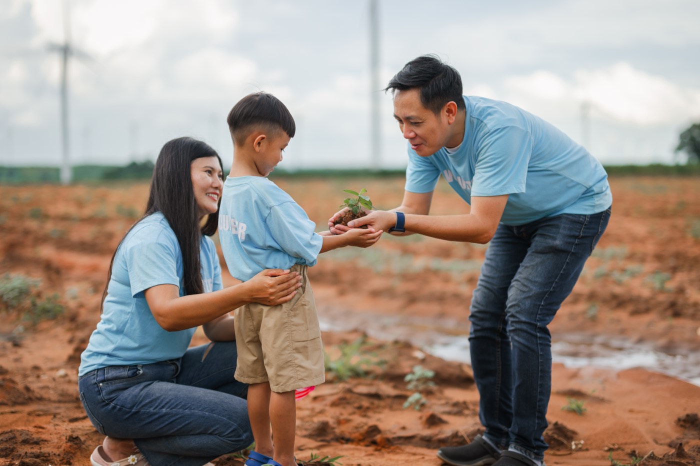 A family planting a young sapling in the ground