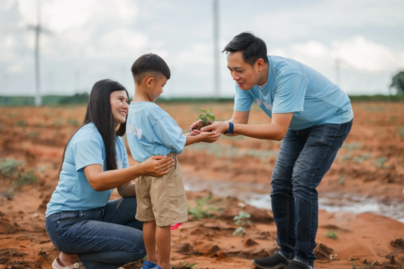 A family planting a young sapling in the ground