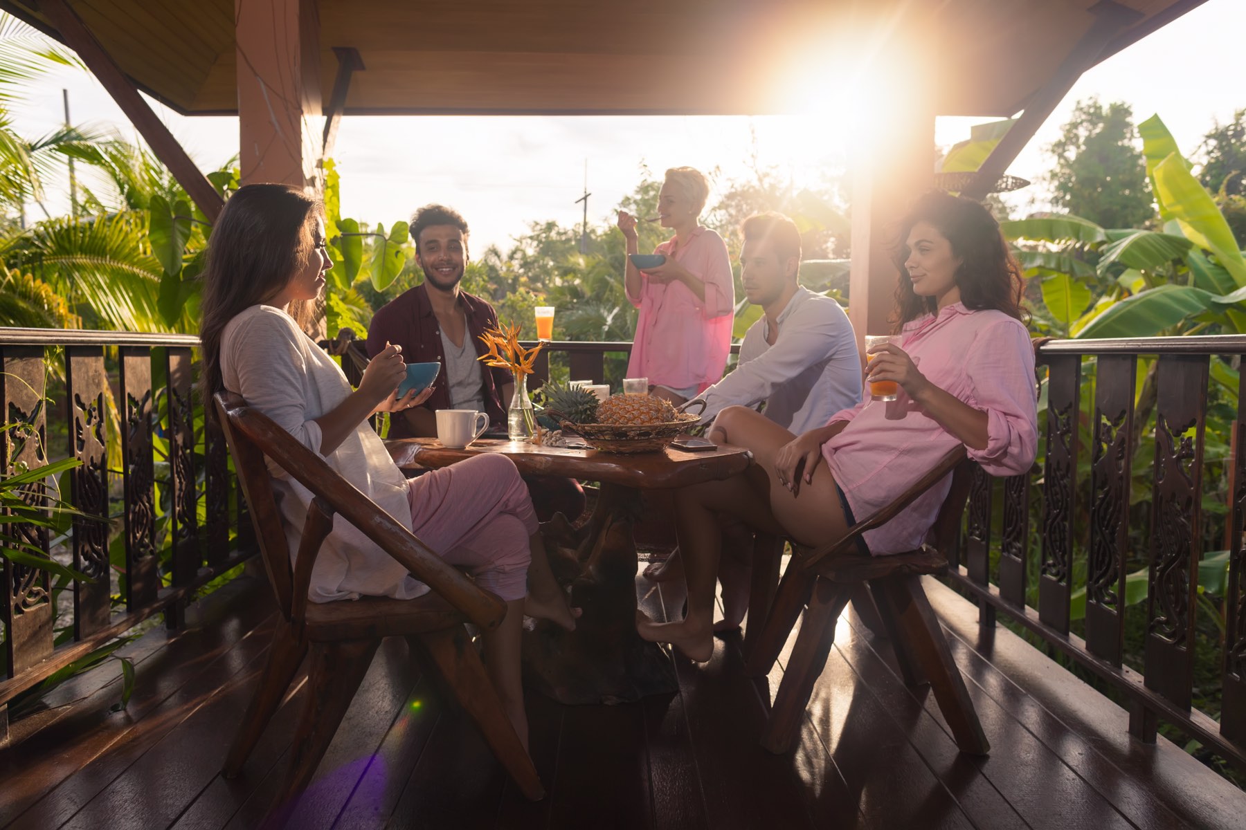 A family around a long table on a wooden veranda at golden hour